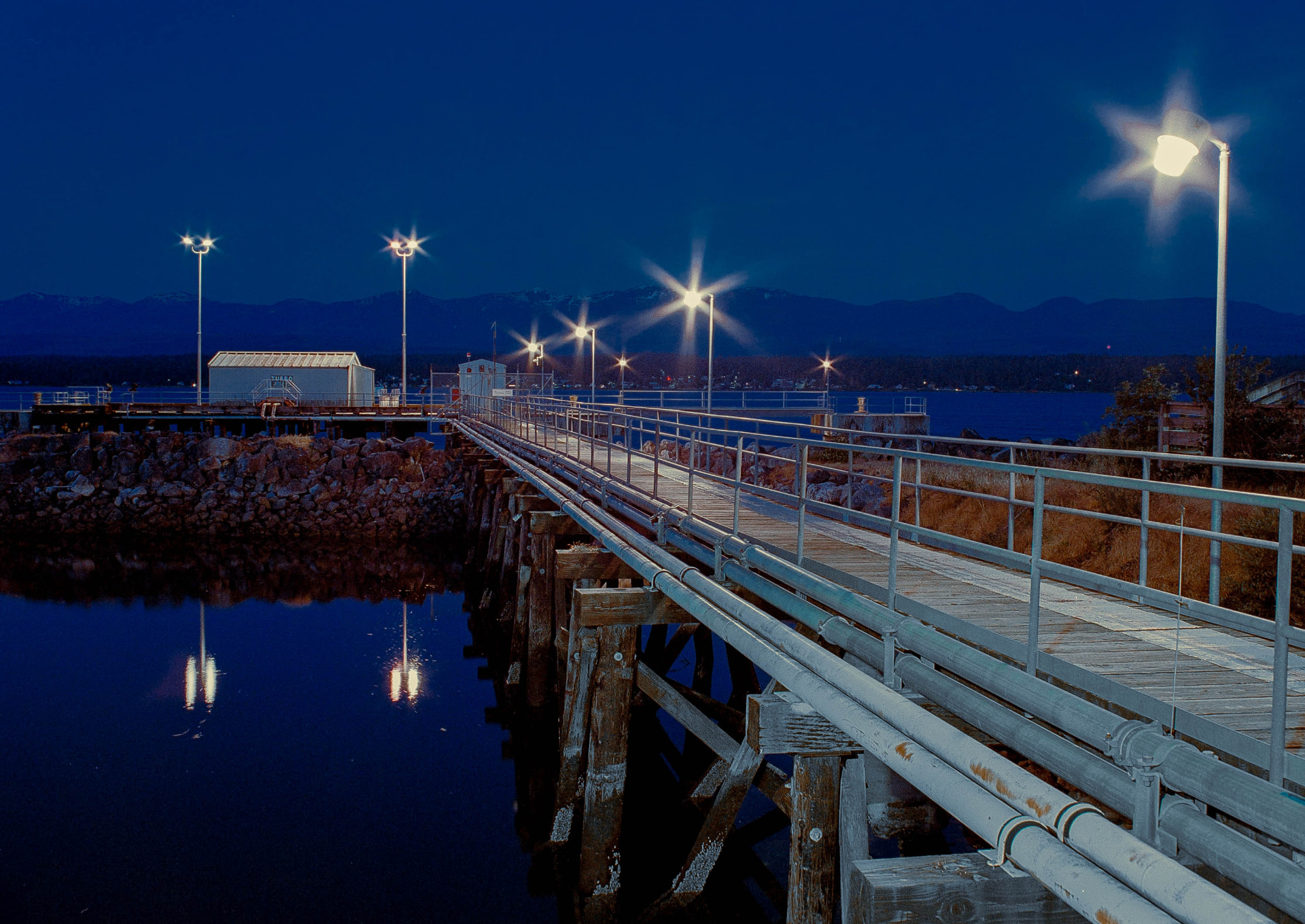 Marina Dock — a lit wooden pier stretching over dark water at blue hour