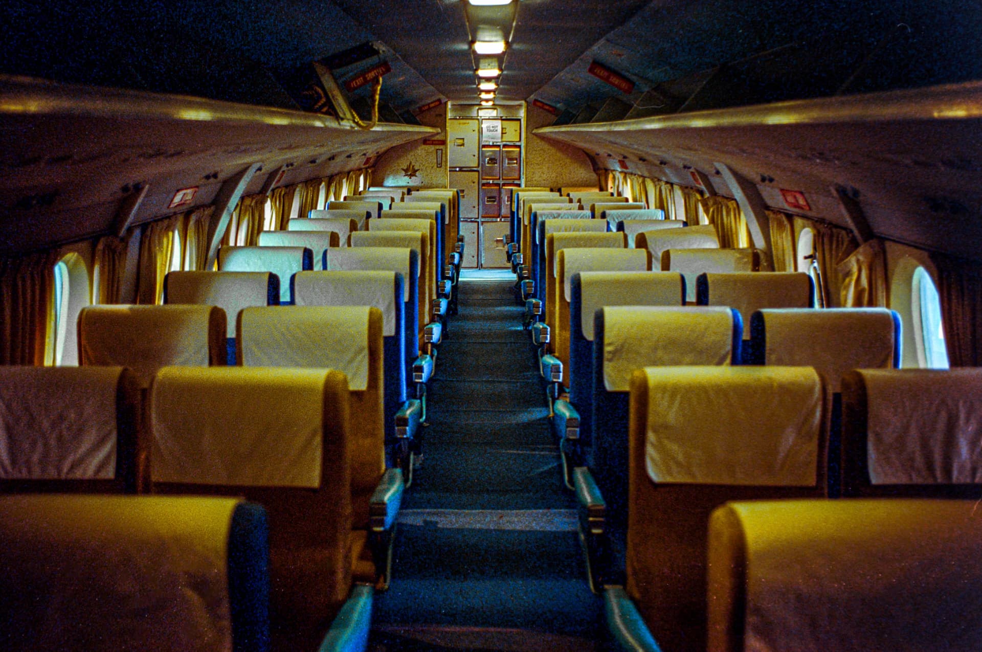 Airplane Interior — symmetrical view down the centre aisle of an empty vintage cabin